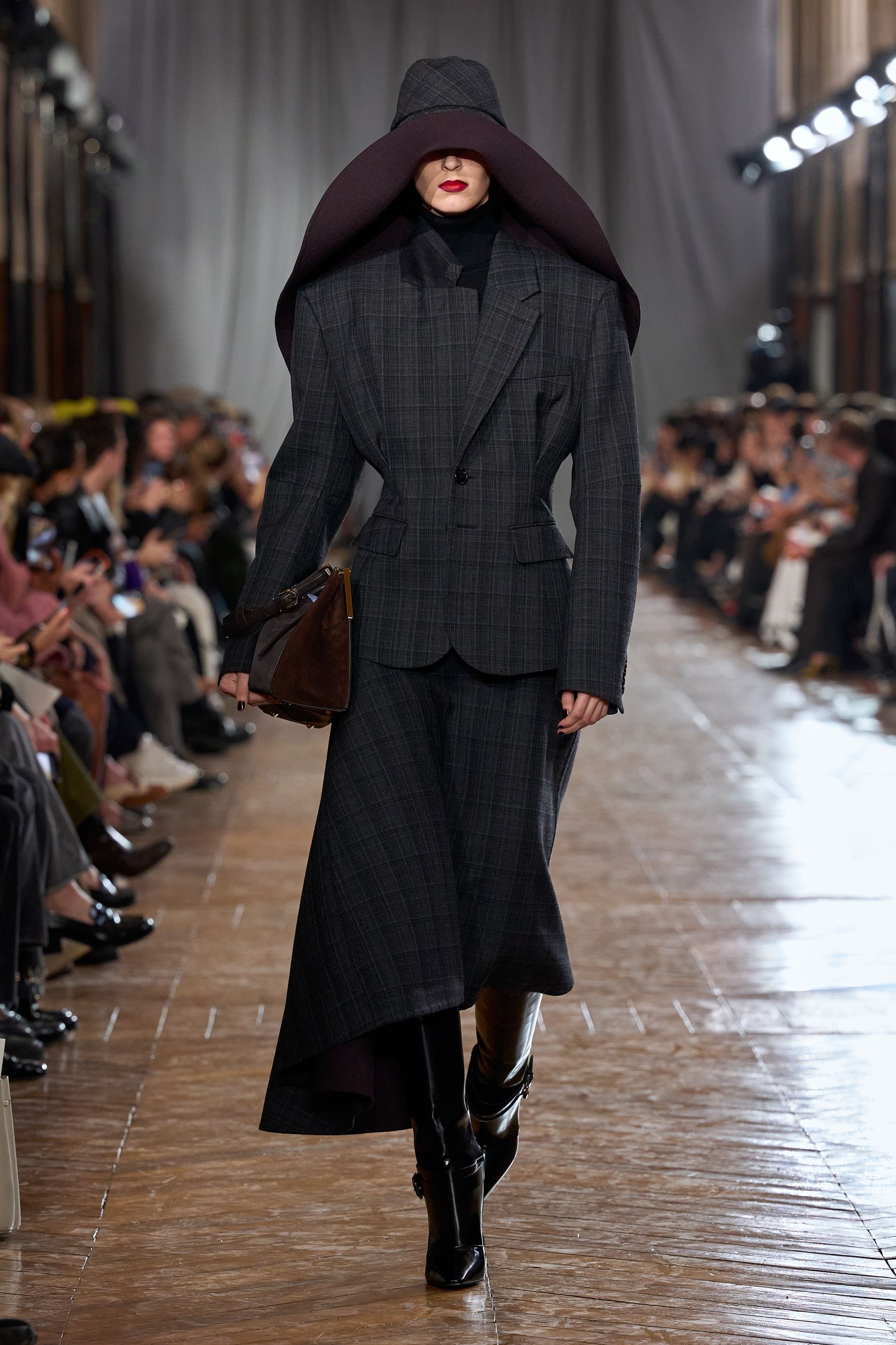 Lanvin 本季回归品牌最经典的巴黎女性气质：结构精准的西装、收腰裙装、深色羊毛套装与戏剧性大檐帽形成一种冷静而克制的奢华。柔软褶皱、细腰剪裁与高靴搭配营造出带有1930年代气息的摩登贵族感，同时通过金属亮片与垂坠流苏礼服让夜晚部分显得华丽而锋利。整场秀像一场巴黎旧贵族的时装电影，优雅却不失力量-顽石频道趋势研究